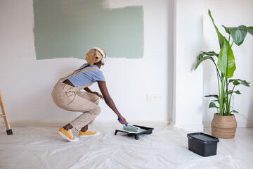 Black painter listening to music and looking at wall