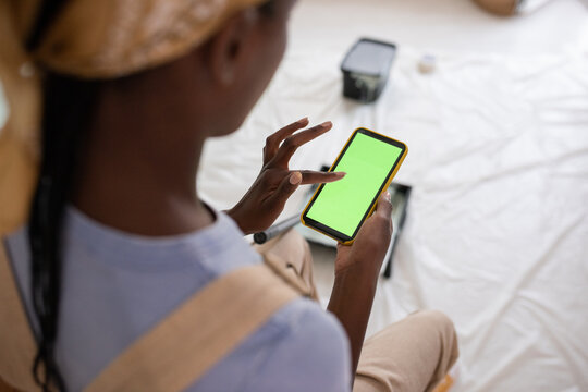 Black female painter using smartphone