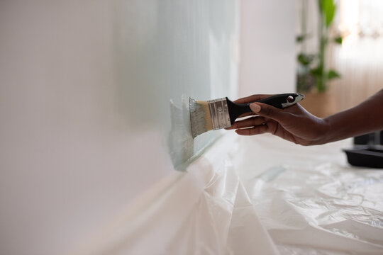 Crop African American woman painting wall