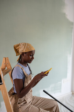 Black woman browsing cellphone during renovation