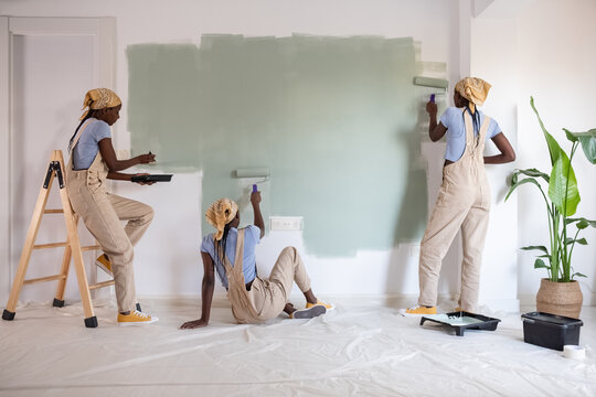 Black woman painting wall with roll and brush
