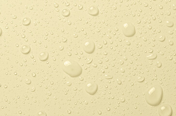Fototapeta na wymiar Drops of micellar water or cosmetic tonic on a yellow background. Closeup, macro photography