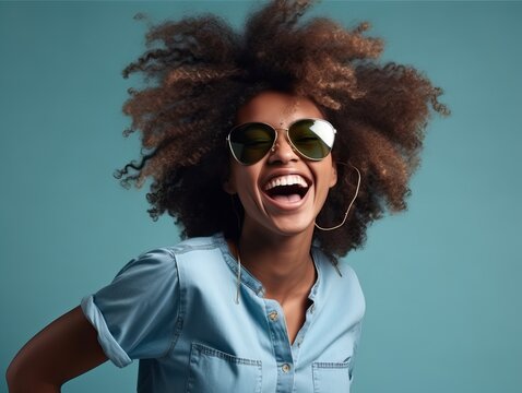 Gl&uuml;ckliche Frau mit Afrolocken tanzt in l&auml;ssigem T-Shirt und Sonnenbrille auf blauem Hintergrund, generative AI.
