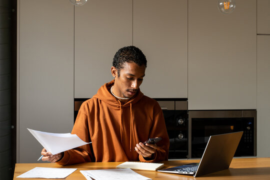 Man paying utility bills from home calculating expenses