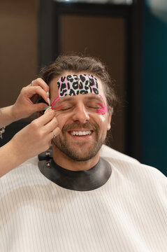 Cosmetologist putting tapes on smiling clients face