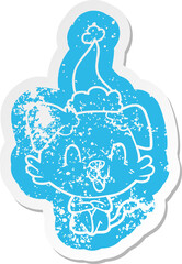 laughing cartoon distressed sticker of a dog wearing santa hat