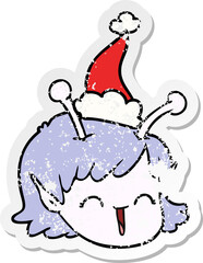 distressed sticker cartoon of a alien space girl face wearing santa hat