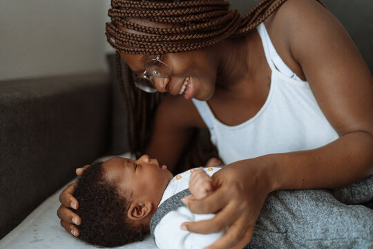 African American mom playing with little kid on couch