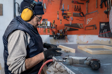 Fototapeta premium Portrait of a professional carpenter in his workshop, where he performs activities related to wood, such as cutting, carving, assembling and finishing wood. 
