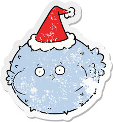 distressed sticker cartoon of a puffer fish wearing santa hat