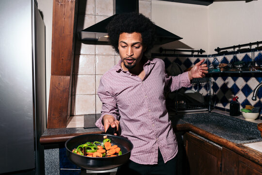 Black man cooking vegetables in a pan