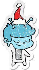 friendly distressed sticker cartoon of a spaceman wearing santa hat