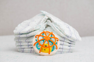 Baby toy on the background of a stack of baby diapers, close-up. Copy space for text