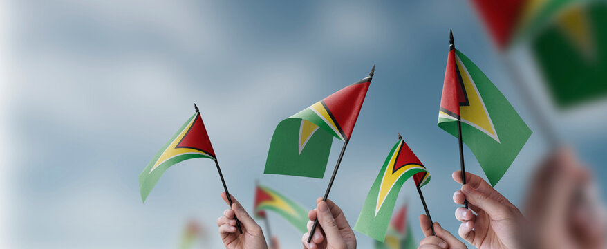 A group of people holding small flags of the Guyana in their hands