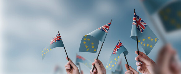 A group of people holding small flags of the Tuvalu in their hands