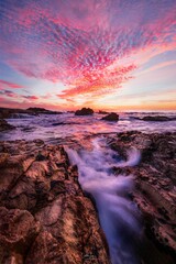 Vertical long exposure shot of a rocky beach at sunset in Cascais, Portugal.
