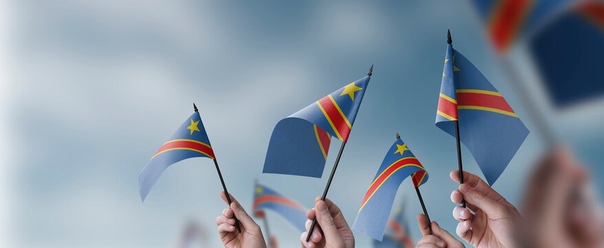 A group of people holding small flags of the Democratic Republic of the Congo in their hands