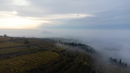 Aerial of the hills covered in the fog in Soave, Verona, Italy with the cloudy sky on background