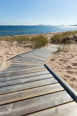 Wooden boardwalk leading to an empty beach in Hanko, Finland, on a sunny day in the summer.