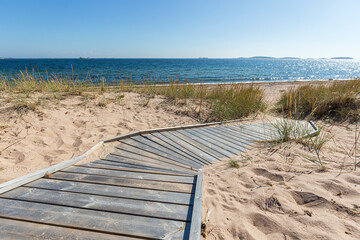Wooden boardwalk leading to an empty beach in Hanko, Finland, on a sunny day in the summer.
