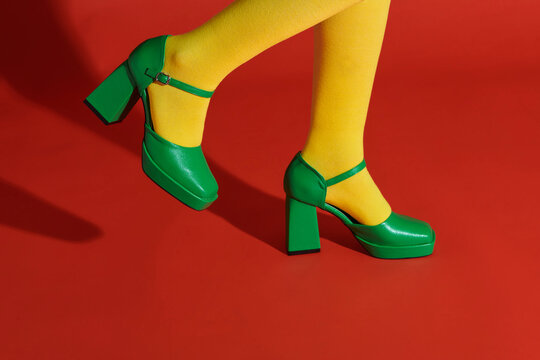 Female legs in green high heel shoes and socks on color background
