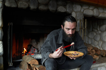 Man eats in front of fire