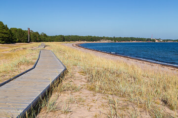 Fototapeta premium Wooden boardwalk at the Tulliniemi beach in Hanko, Finland, on a sunny day in the summer.