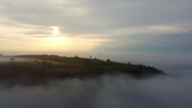 Aerial of the hills covered in the fog in Soave, Verona, Italy with the cloudy sky on background
