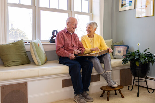 Senior Citizen couple retired  at home laugh at family photo album 