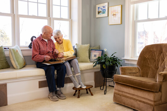  Senior Citizen couple at home laugh at family photos