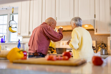 Senior Citizen couple family at home cooking together tasting soup