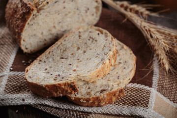 Sliced fresh baked whole grain bread with oats, flax seeds and sesame seeds on rustic wooden board. Bakery products
