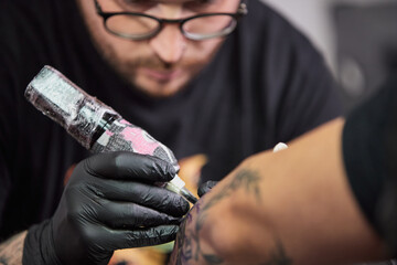 Tattoo of a lion on the arm of the client in the salon. Tattoo artist working on a client's arm in...