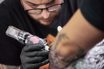 Tattoo of a lion on the arm of the client in the salon. Tattoo artist working on a client's arm in his studio.