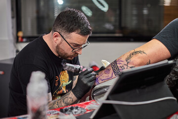 Tattoo of a lion on the arm of the client in the salon. Tattoo artist working on a client's arm in his studio.