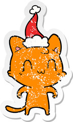 distressed sticker cartoon of a happy cat wearing santa hat