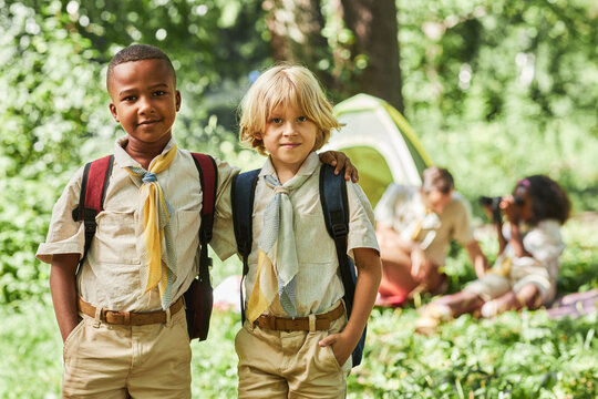 Waist up portrait of two boy scouts looking at camera while camping with school group, copy space