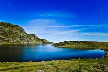 Fototapeta na wymiar Seven Rila lakes view with green fields and mountains around, clear sky background