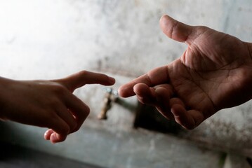 Closeup of hands reaching to touch against a gray background