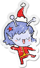 happy alien girl distressed sticker cartoon of a wearing santa hat