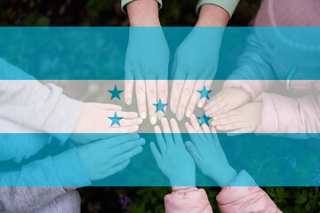 Hands of kids on background of Honduras flag. Honduran patriotism and unity concept.