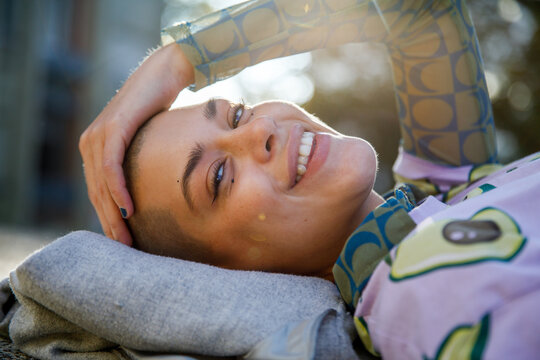 Portrait of happy woman lying on her back outdoors at park