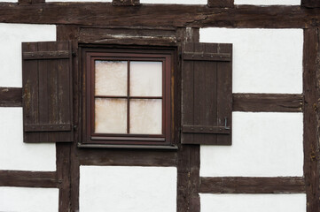Detail of white half-timbered cottage window with shutters