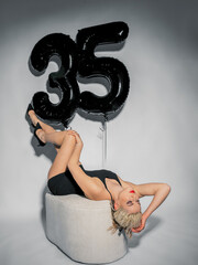 Lovely blonde evening dress and balloons 35 . Celebrates his birthday. Eating cake. Pink background.