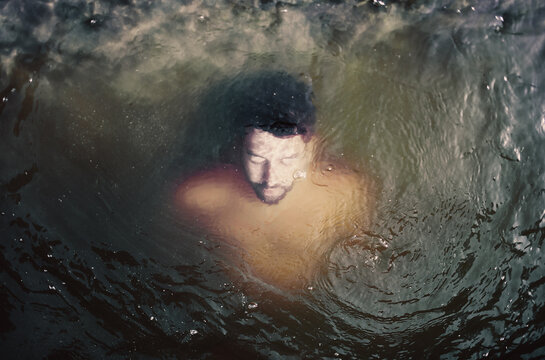 Relaxed man inside surreal dark water