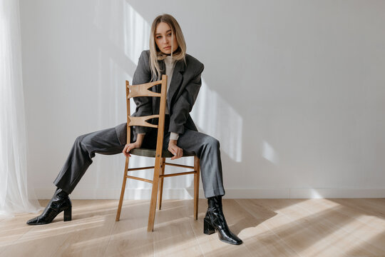 Trendy woman sitting on chair with outstretched legs