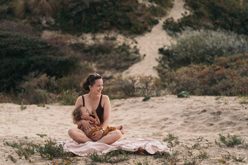 Mom feeding and holding her child at the beach
