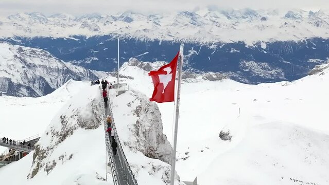 Swiss flag over a peak walk in the alps aerial view by drone