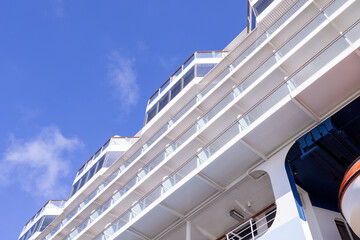 A close up on a large cruise ship in the sunshine showing the cruise ships balconies on a hot sunny summers day.