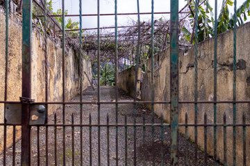 An old abandoned house behind a rusty old metal gate, located in the town of Funchal in Madeira...